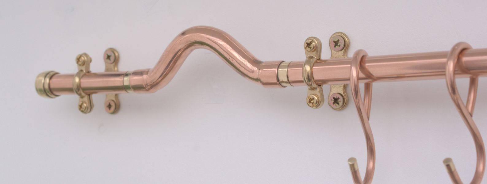 Half-circle bend copper pan rail in modern industrial style, wall-mounted with brass brackets